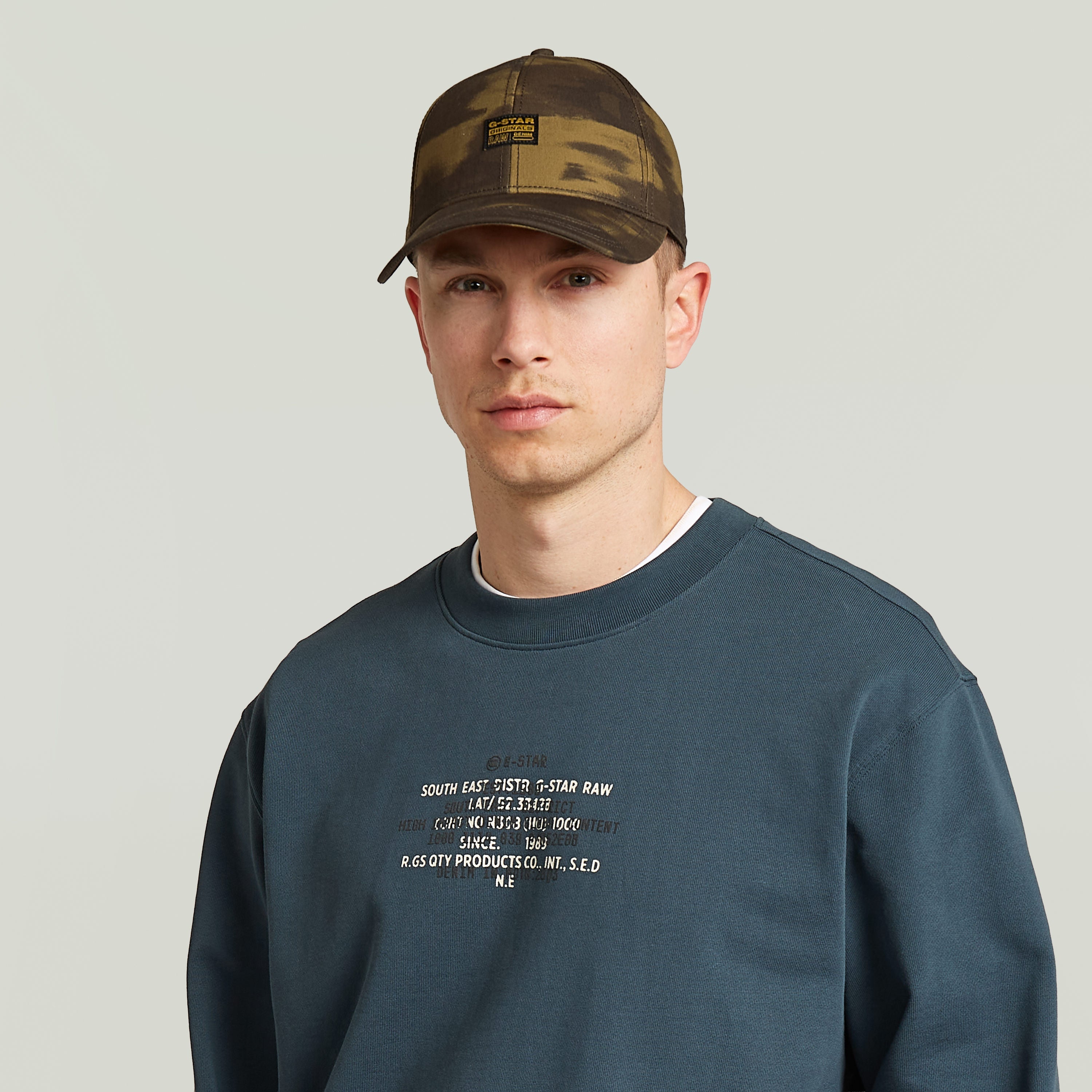 G-STAR Originals baseball cap worn by a young man with a blue sweatshirt and neutral background.