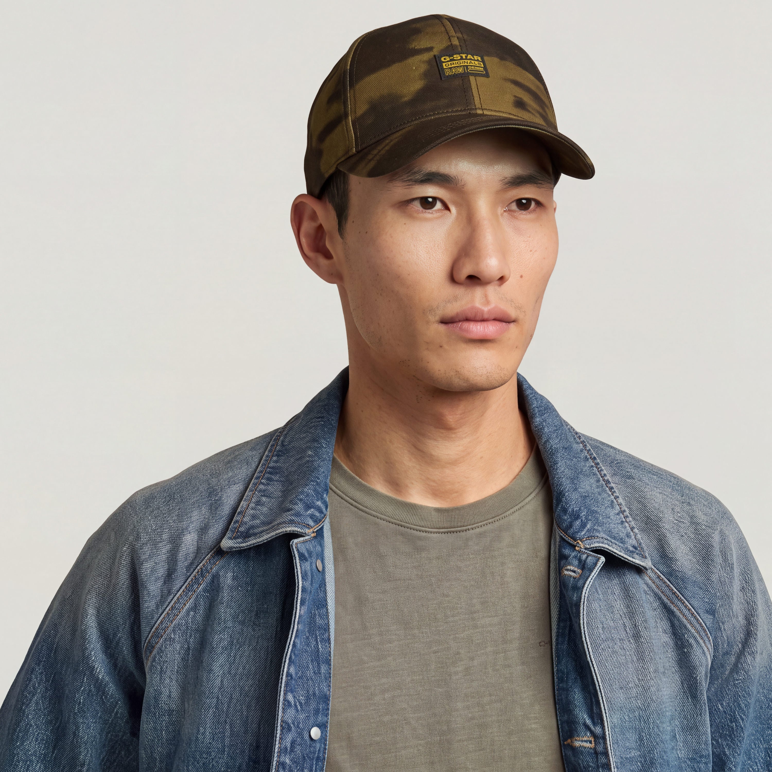 G-STAR Originals baseball cap worn by a man with denim jacket and olive t-shirt, showcasing the camouflage design.