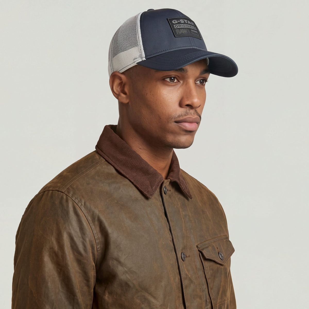 Hombre usando una gorra baseball trucker cap con cierre de clip y estampado G-STAR en la parte delantera.