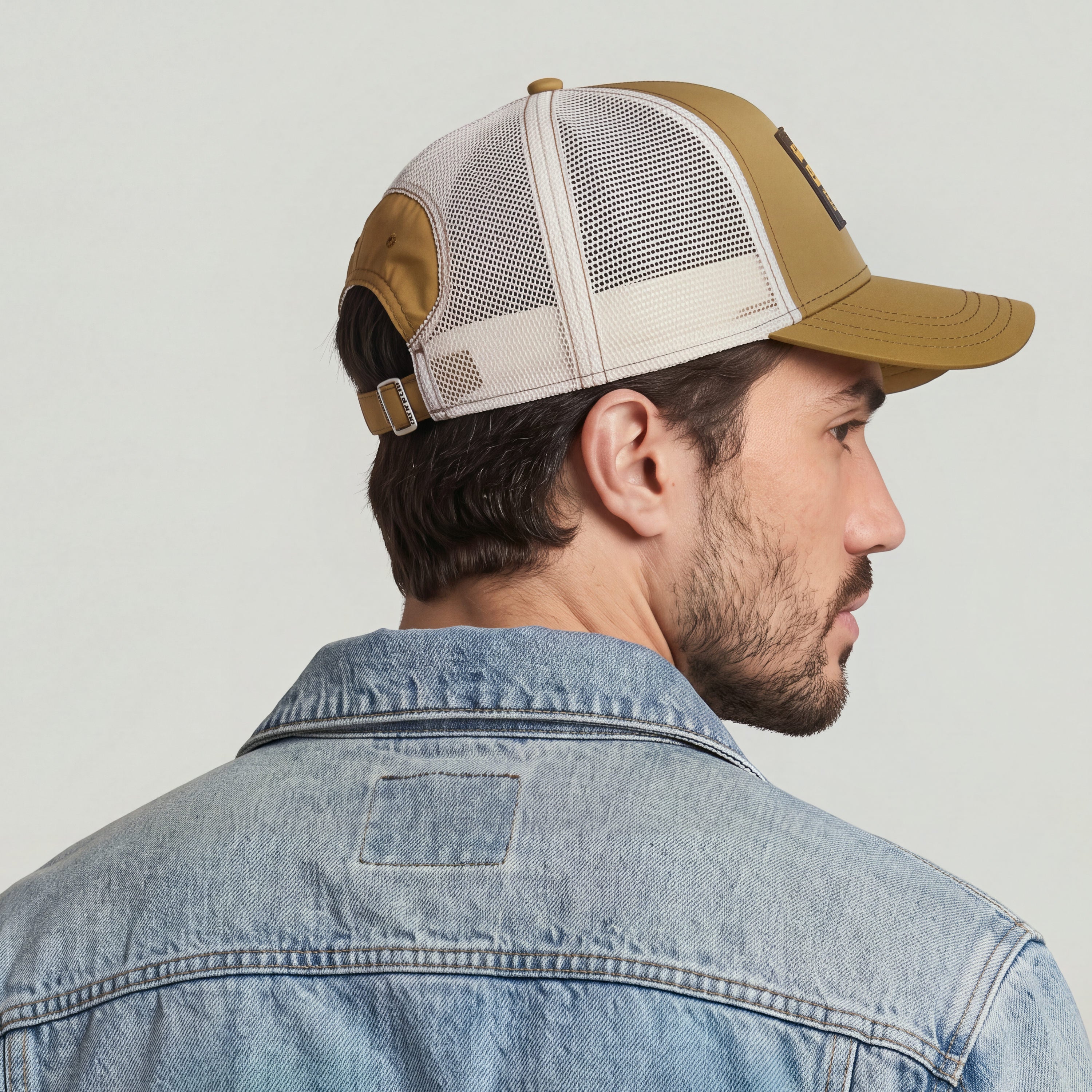 Baseball trucker cap with clip closure displayed on a man wearing a denim jacket.