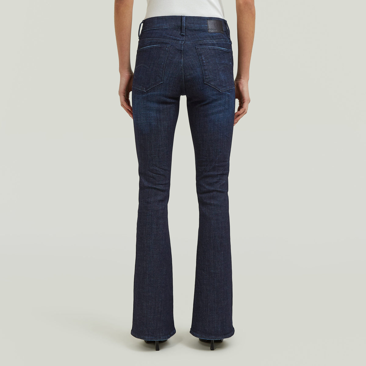 Mujer usando 3301 flare jeans con corte de bota desde la parte trasera, mostrando el diseño y detalles.