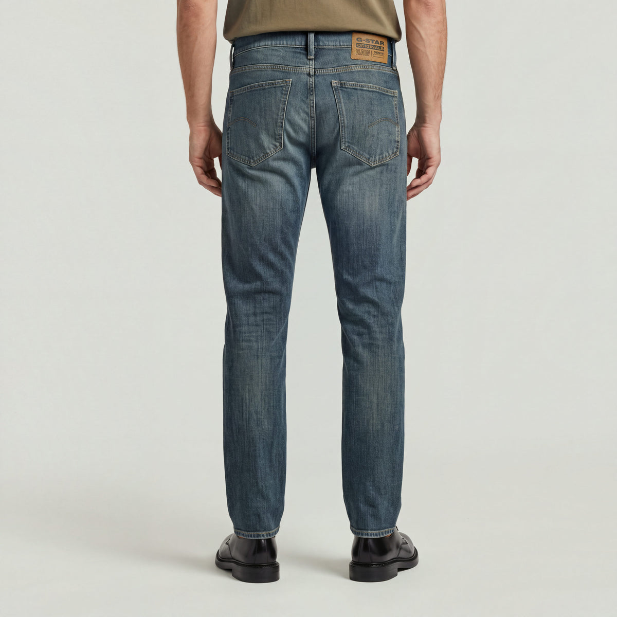 Hombre usando Mosa straight jeans, vista trasera mostrando detalles de diseño y etiqueta.