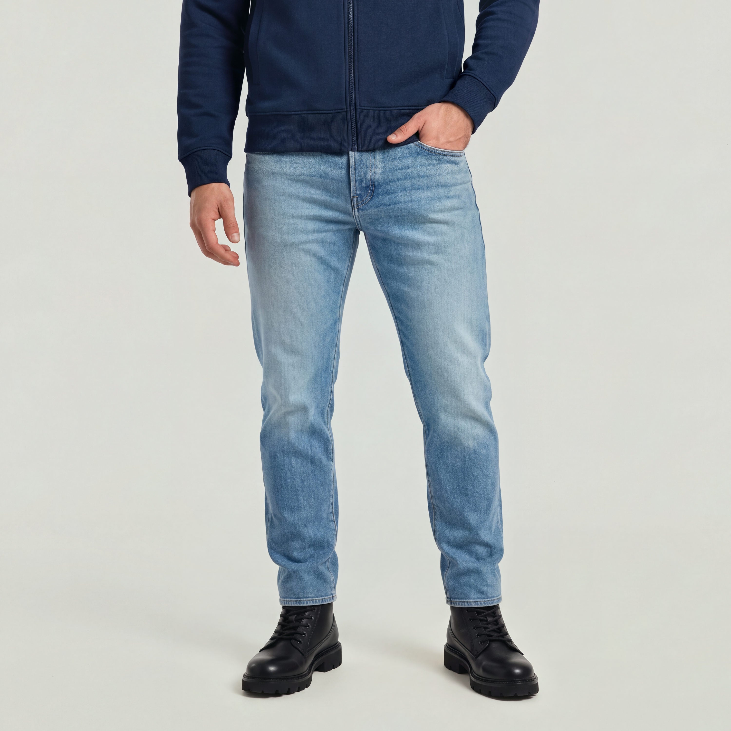Modelo vistiendo Streem Slim Tapered Jeans, jeans de corte slim tapered jeans for men, con detalle de cierre y botines.