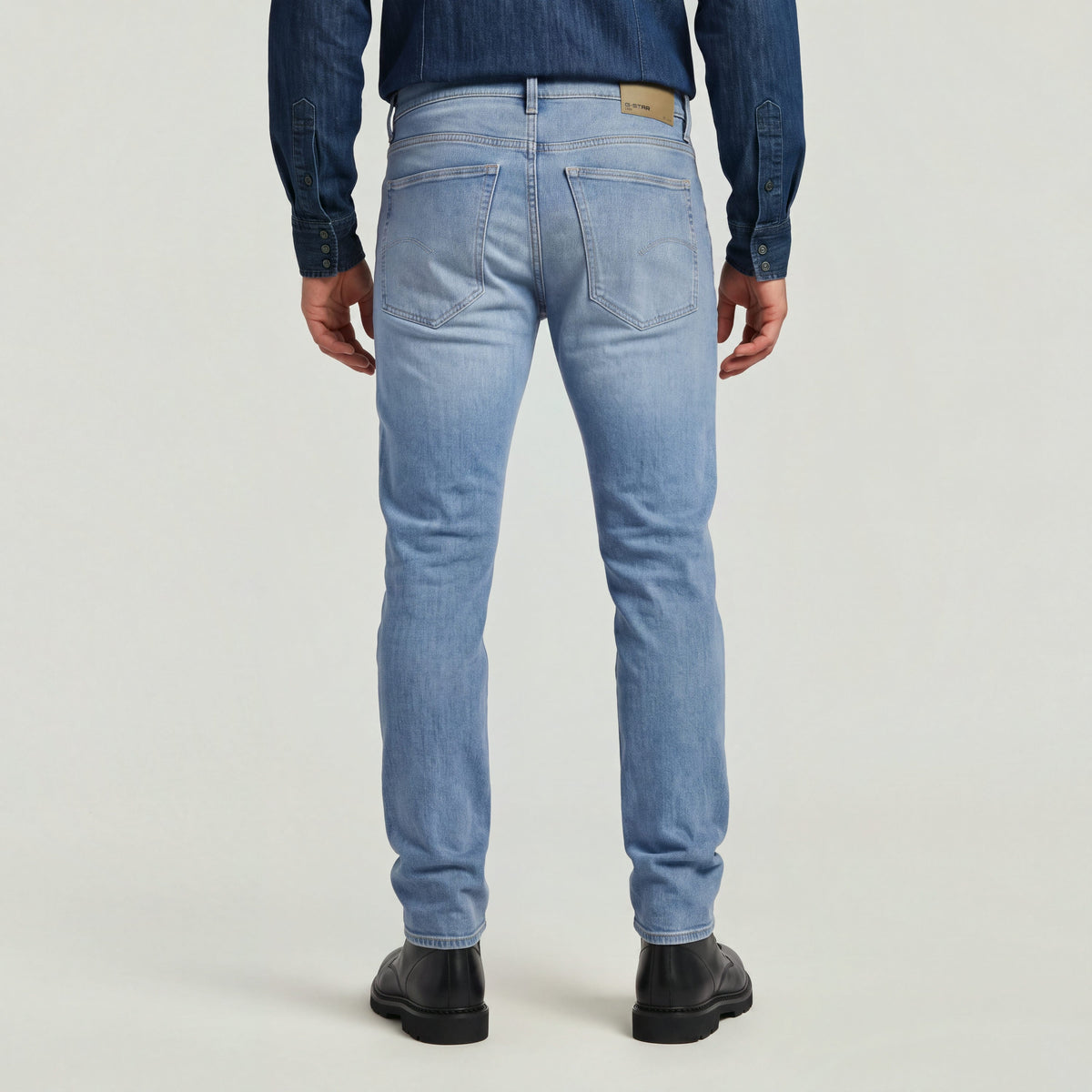 Hombre usando jeans de corte slim moderno, vista trasera en color claro, slim tapered jeans for men.