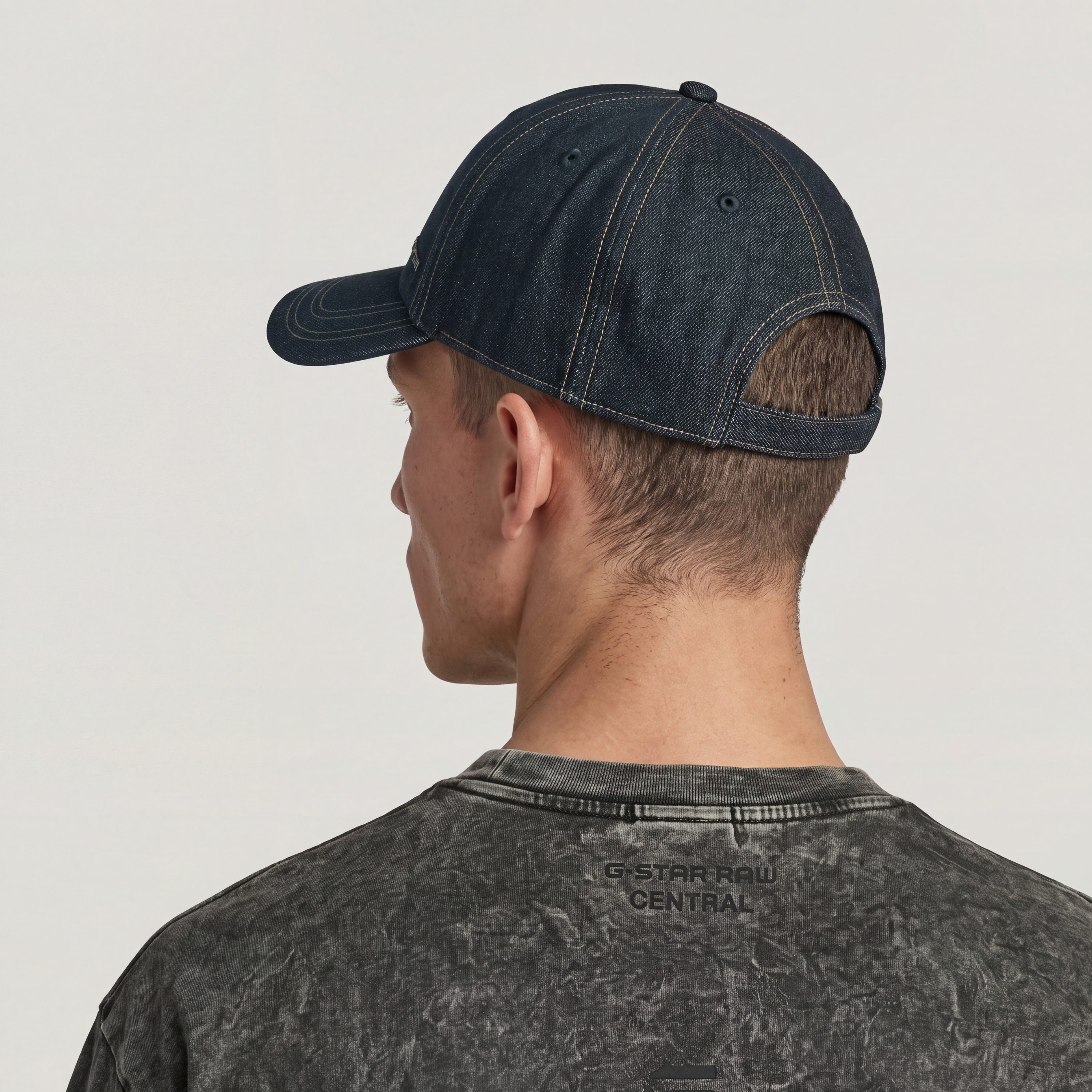 Avernus baseball cap with adjustable clip worn by a person with short hair, showing the back and side view.
