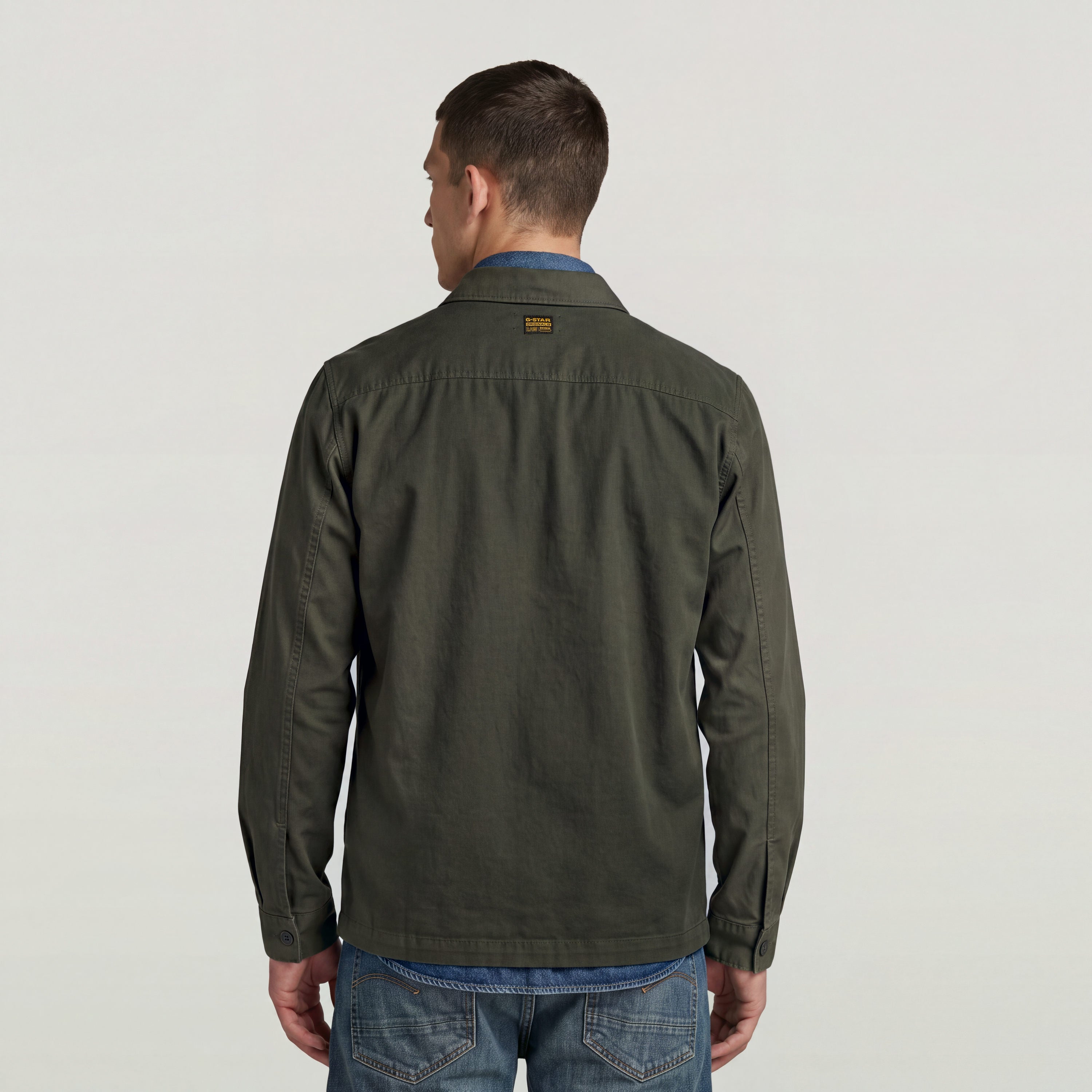 Back view of a model wearing a classic lightweight overshirt in dark green with a casual look.