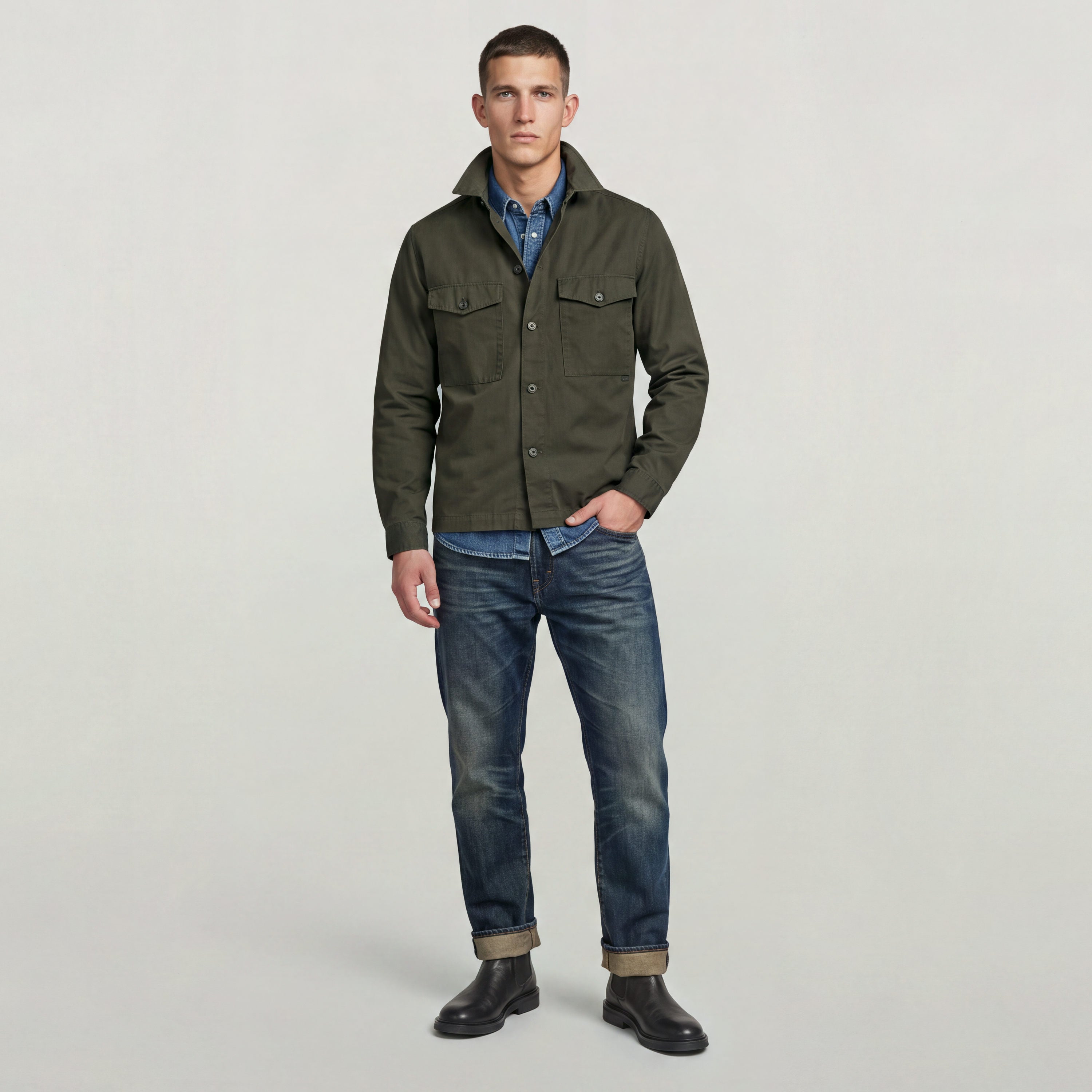 Hombre usando una sobrecamisa Core Lightweight, un clásico lightweight overshirt, con jeans y botas en un fondo neutral.