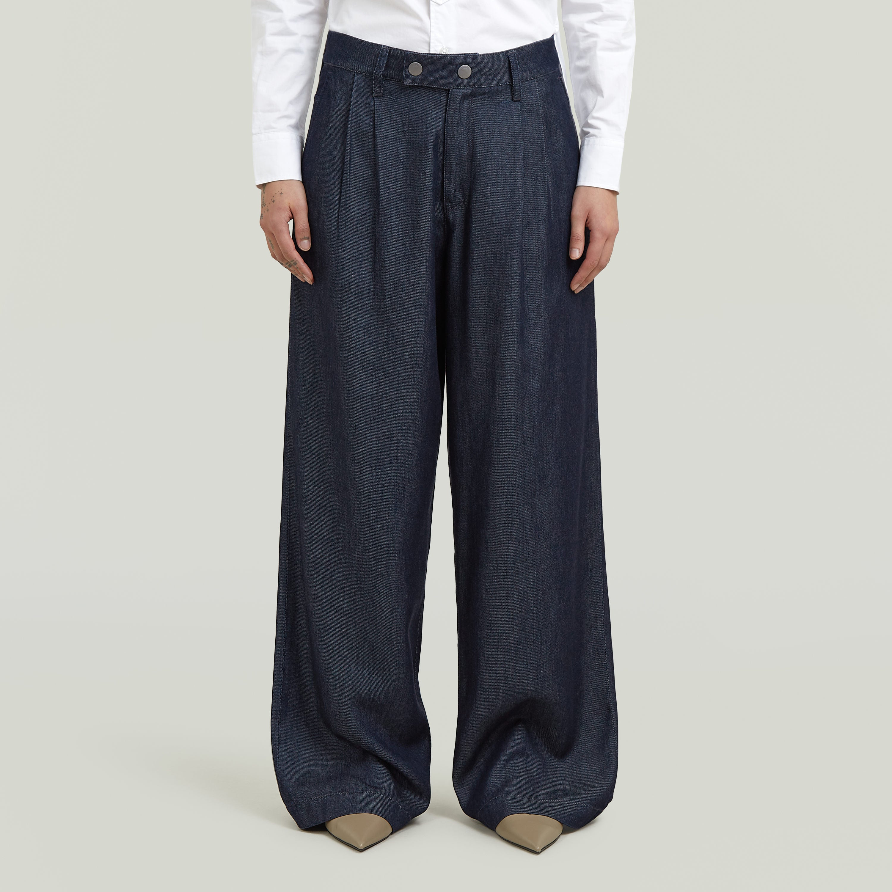 Model wearing pleated chino pants, showcasing a classic straight cut and modern design.