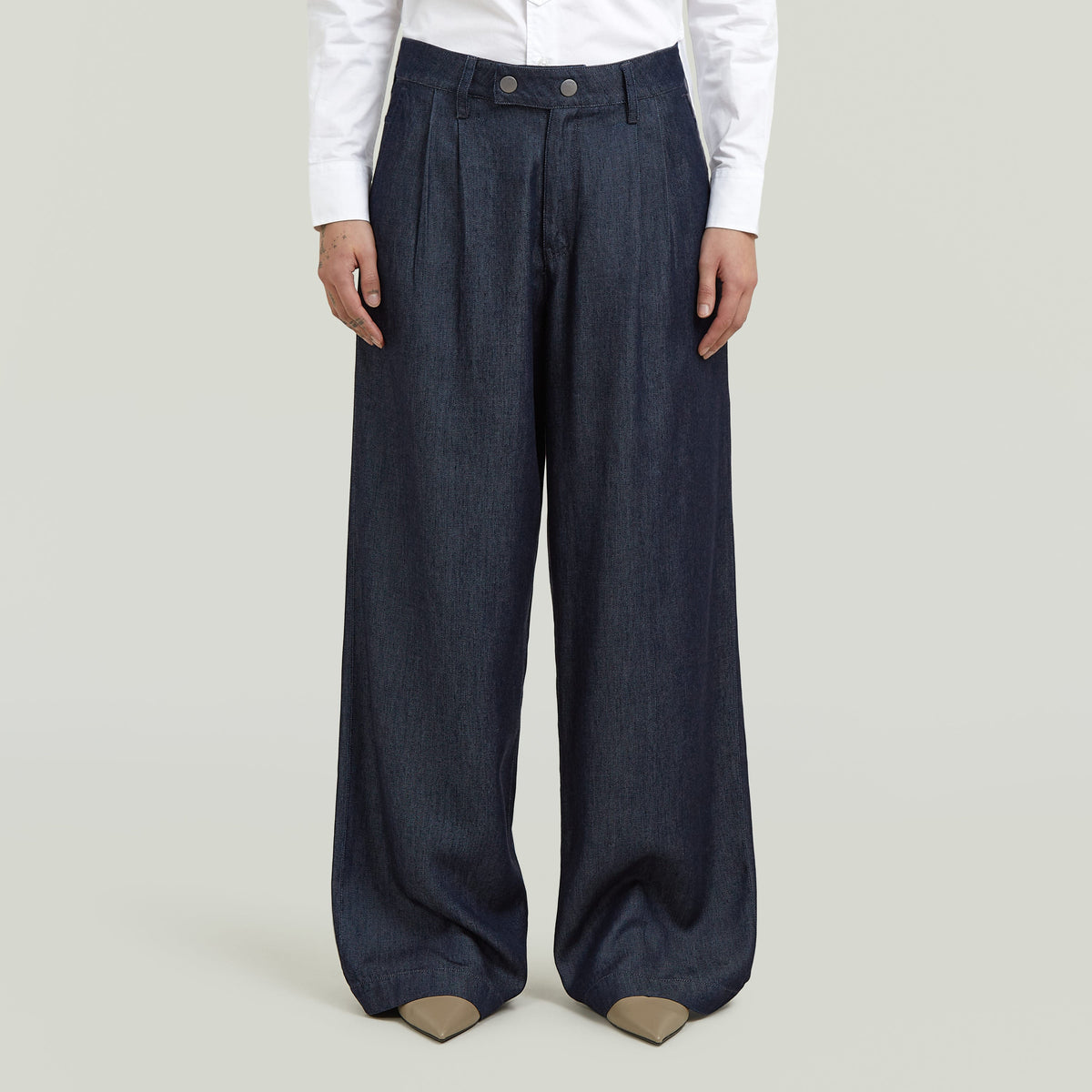 Model wearing pleated chino pants, showcasing a classic straight cut and modern design.