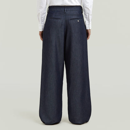 Vista trasera de pantalones pleated chino pants en color oscuro, con detalles de bolsillo y ajuste amplio.