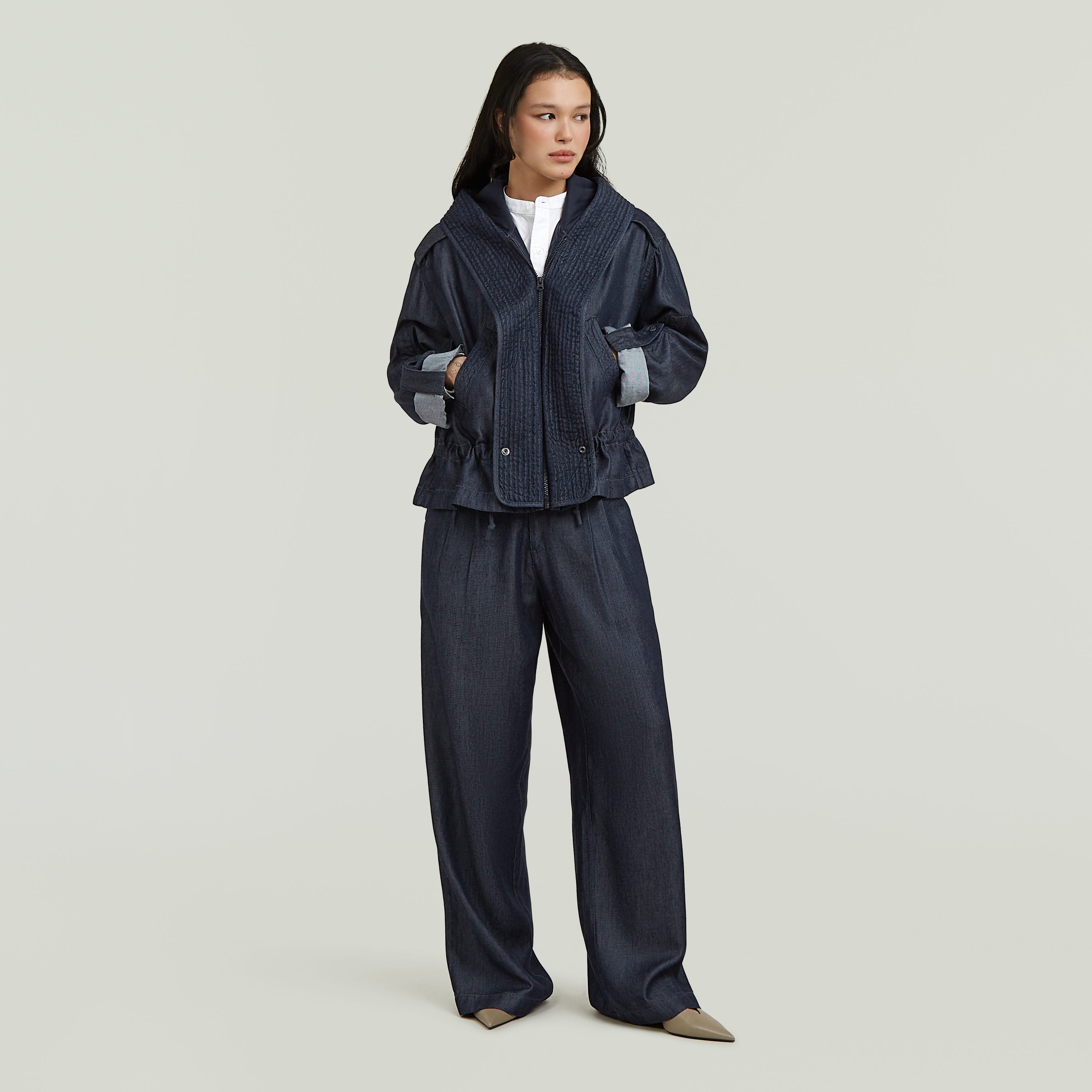 El Pleated Chino ofrece un corte recto con tiro medio y pernera larga, combinando un diseño clásico con una confección moderna.