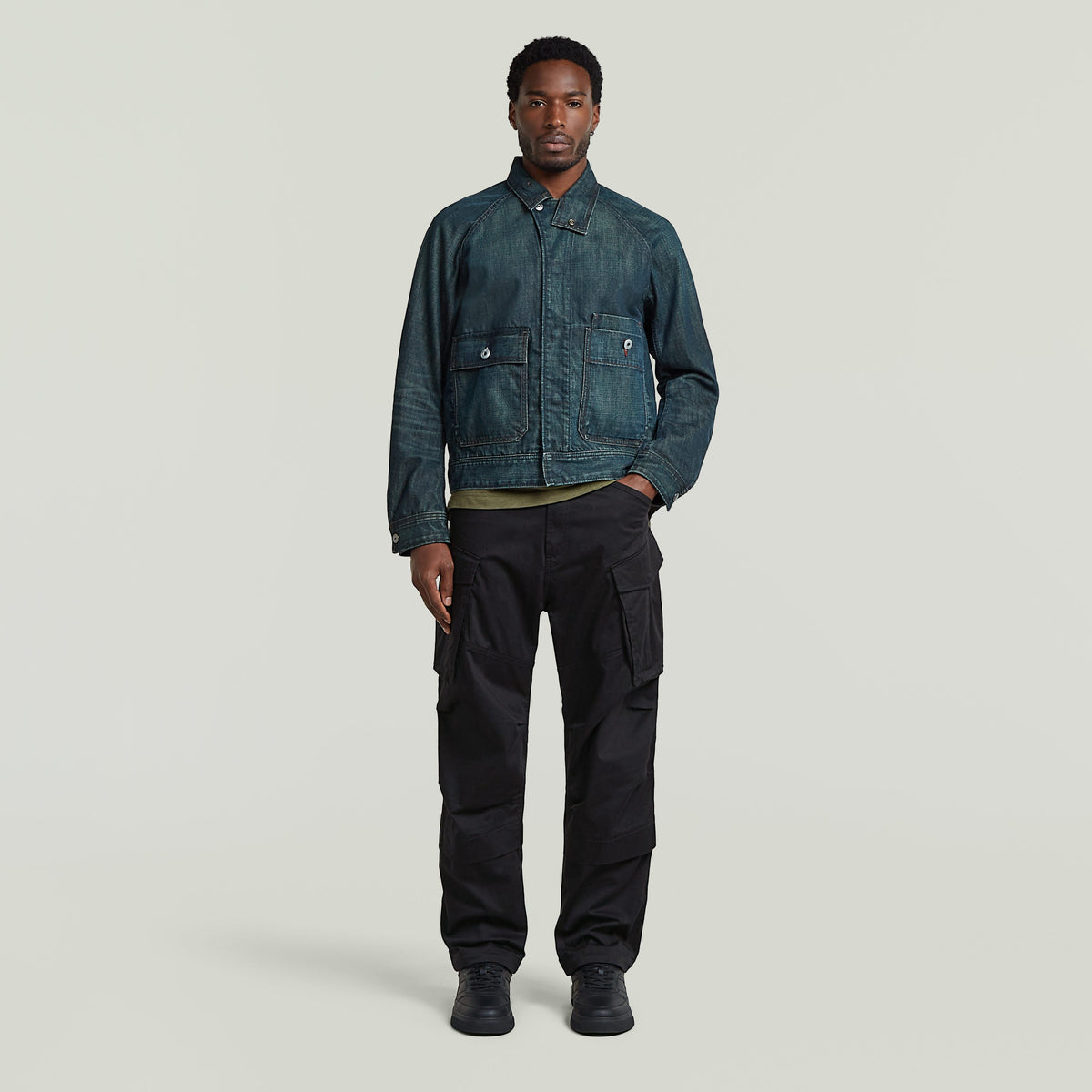 classic battle denim jacket worn by a model, featuring a straight cut with front pockets and a unique greenish indigo hue.
