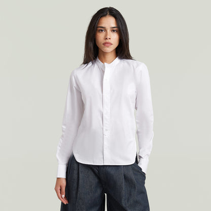 Woman wearing a classic button-up long sleeve shirt in white with a high collar.