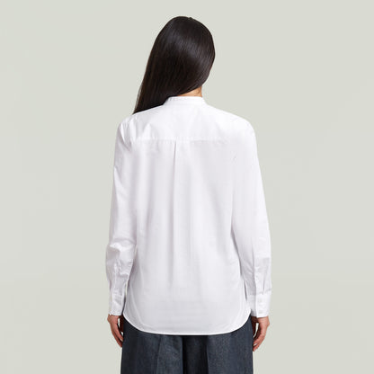 Back view of a woman wearing a classic button-up long sleeve shirt, showcasing its elegant design and button closure.