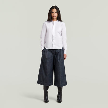 Model wearing a classic button-up long sleeve shirt paired with wide-leg pants.