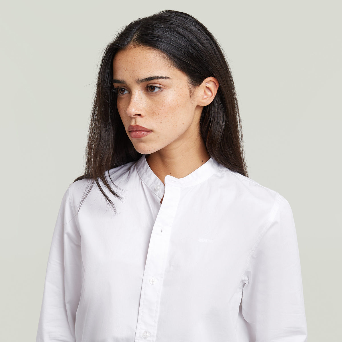 Stylish woman wearing a classic button-up long sleeve shirt with a high collar.