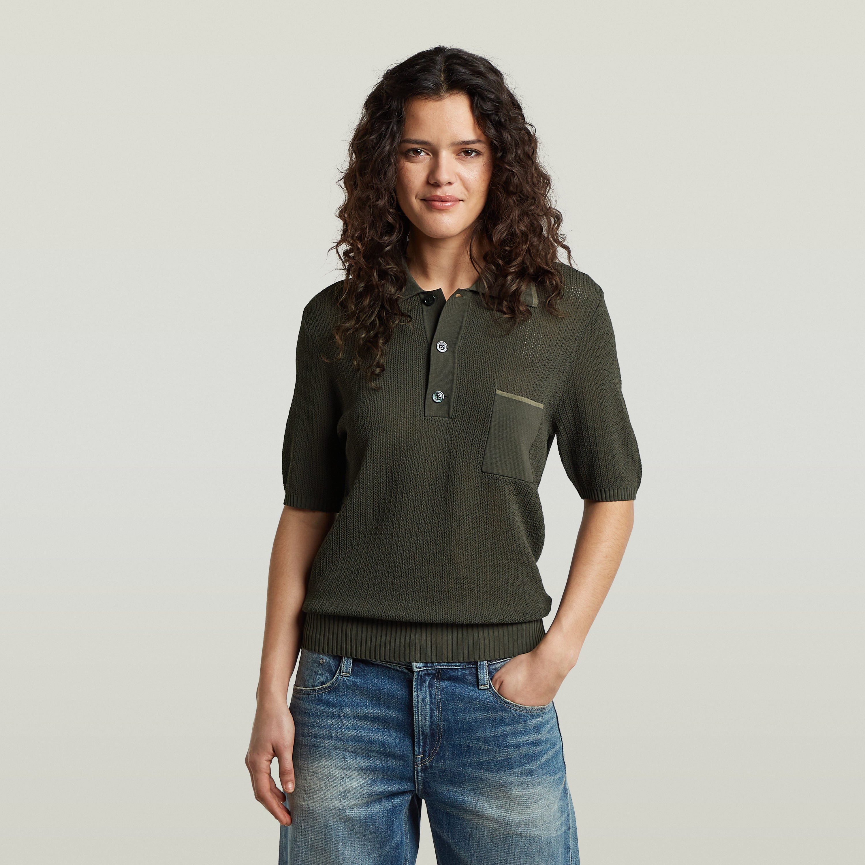 Model wearing a classic knit polo shirt with a collar and button closure in an olive green color.