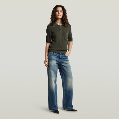 Model wearing a classic knit polo shirt with grey jeans, showcasing a casual and stylish look.