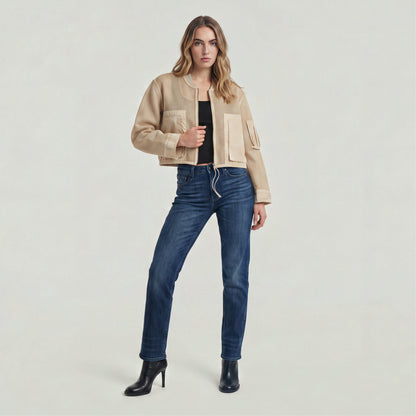 Woman wearing a mixed media relaxed zip thru sweater with jeans and black boots on a neutral background.