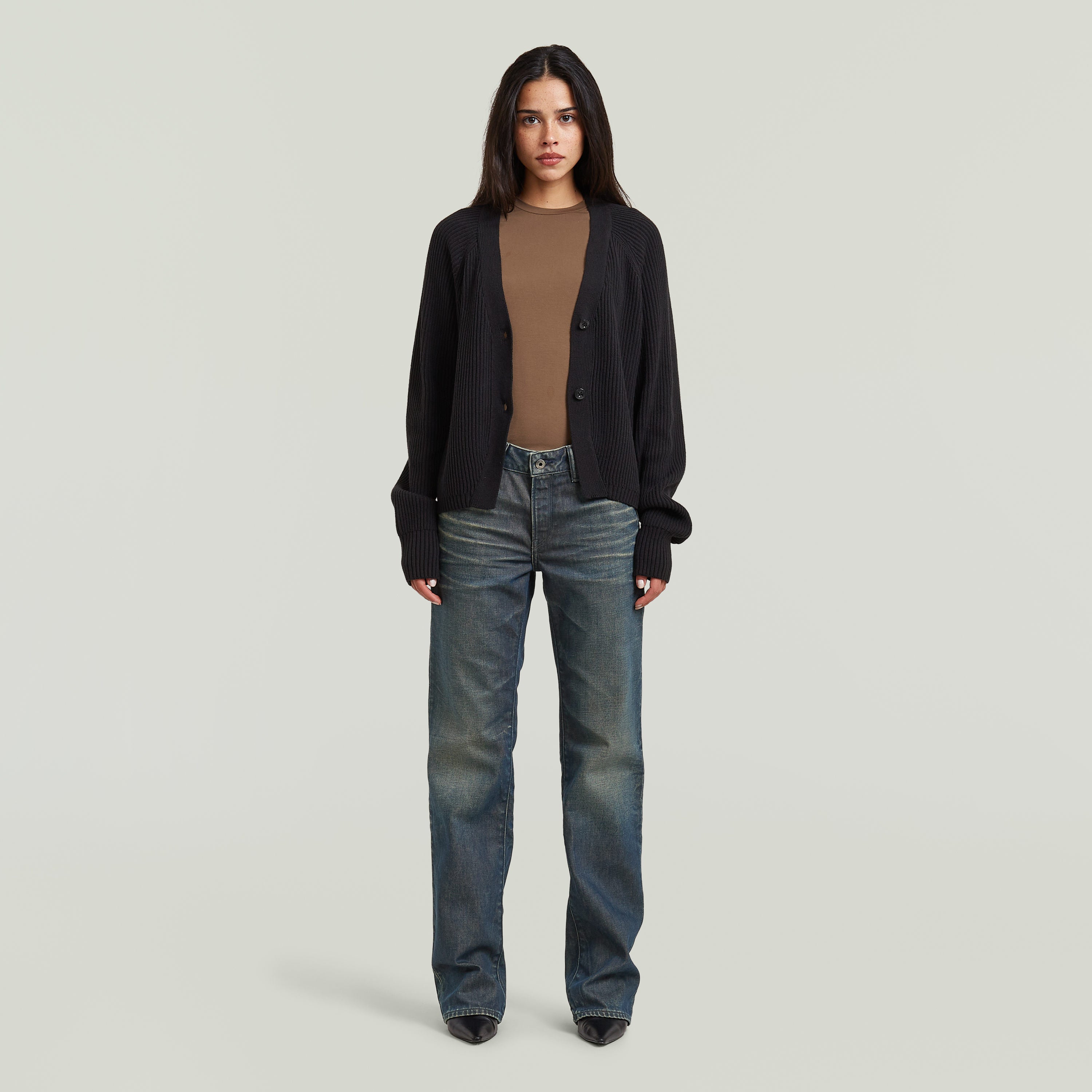 Mujer que lleva un cárdigan entallado cuello V con cierre de corchetes y jeans.