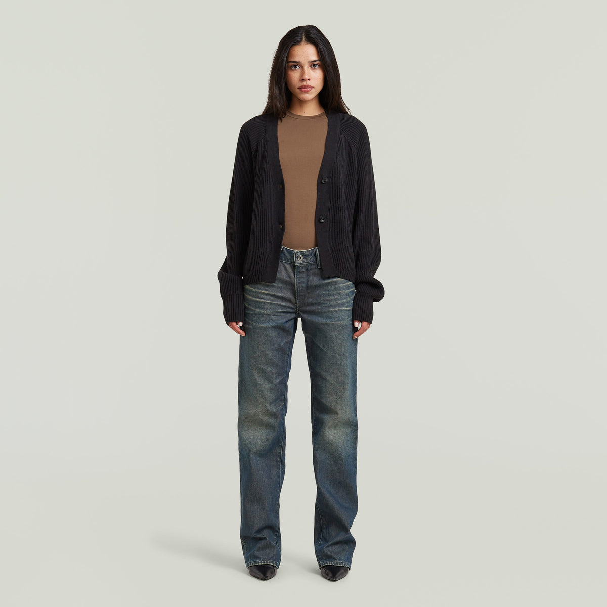 Mujer que lleva un cárdigan entallado cuello V con cierre de corchetes y jeans.
