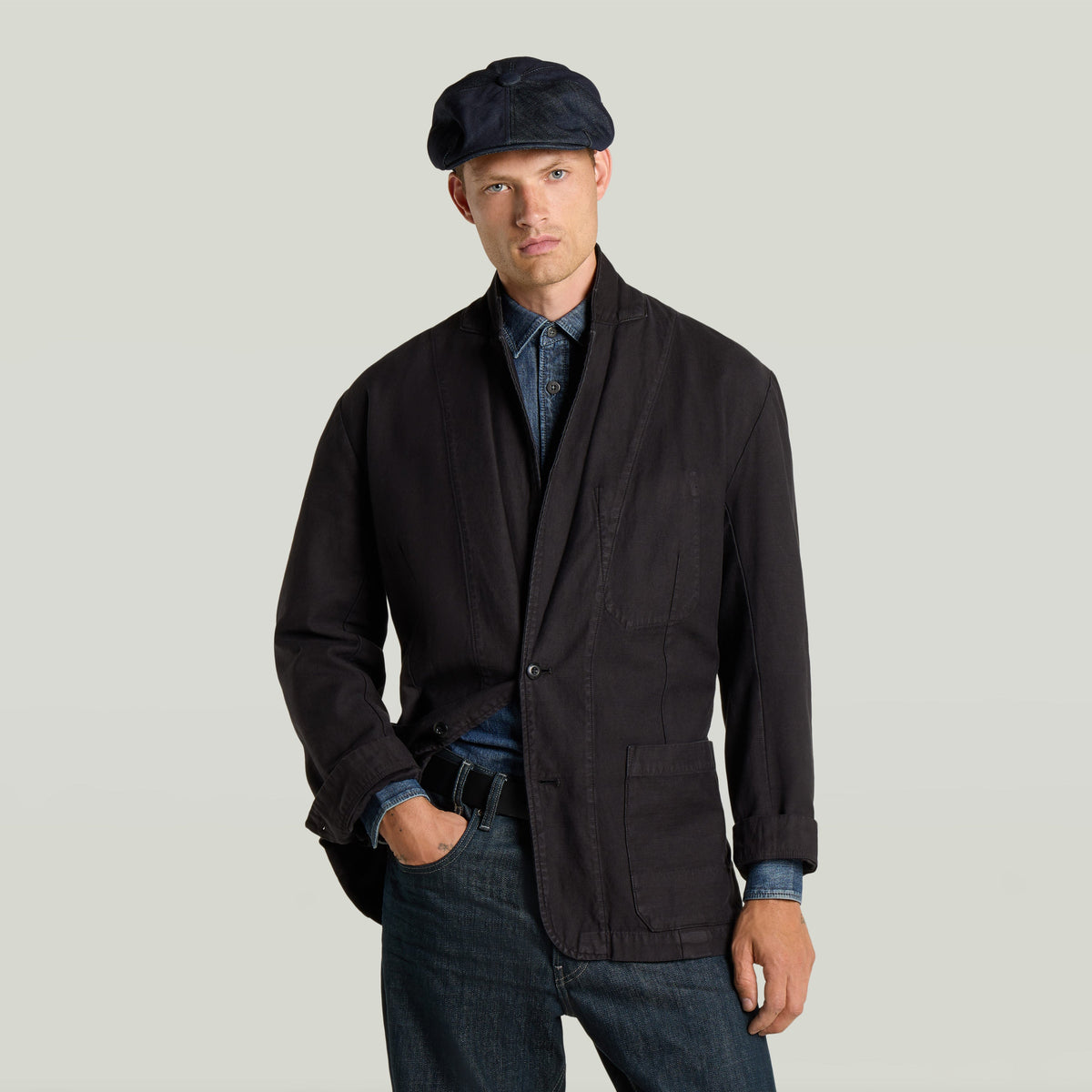 Casual sport blazer worn by a man with a cap, featuring a loose fit and classic lapel design.