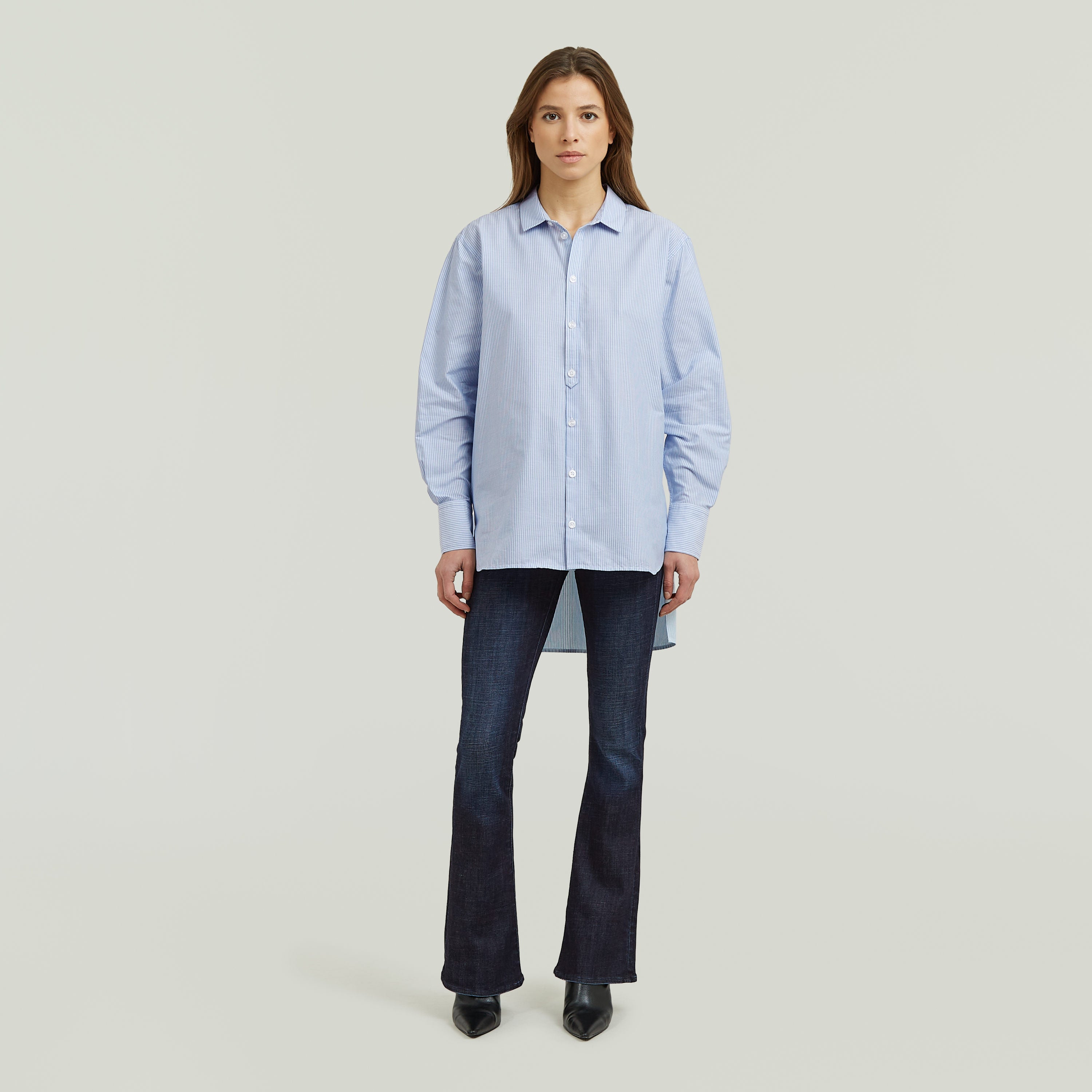 Mujer vistiendo la camisa Relaxed Step Hem con cuello mao y bajo escalonado, combinada con pantalones oscuros.