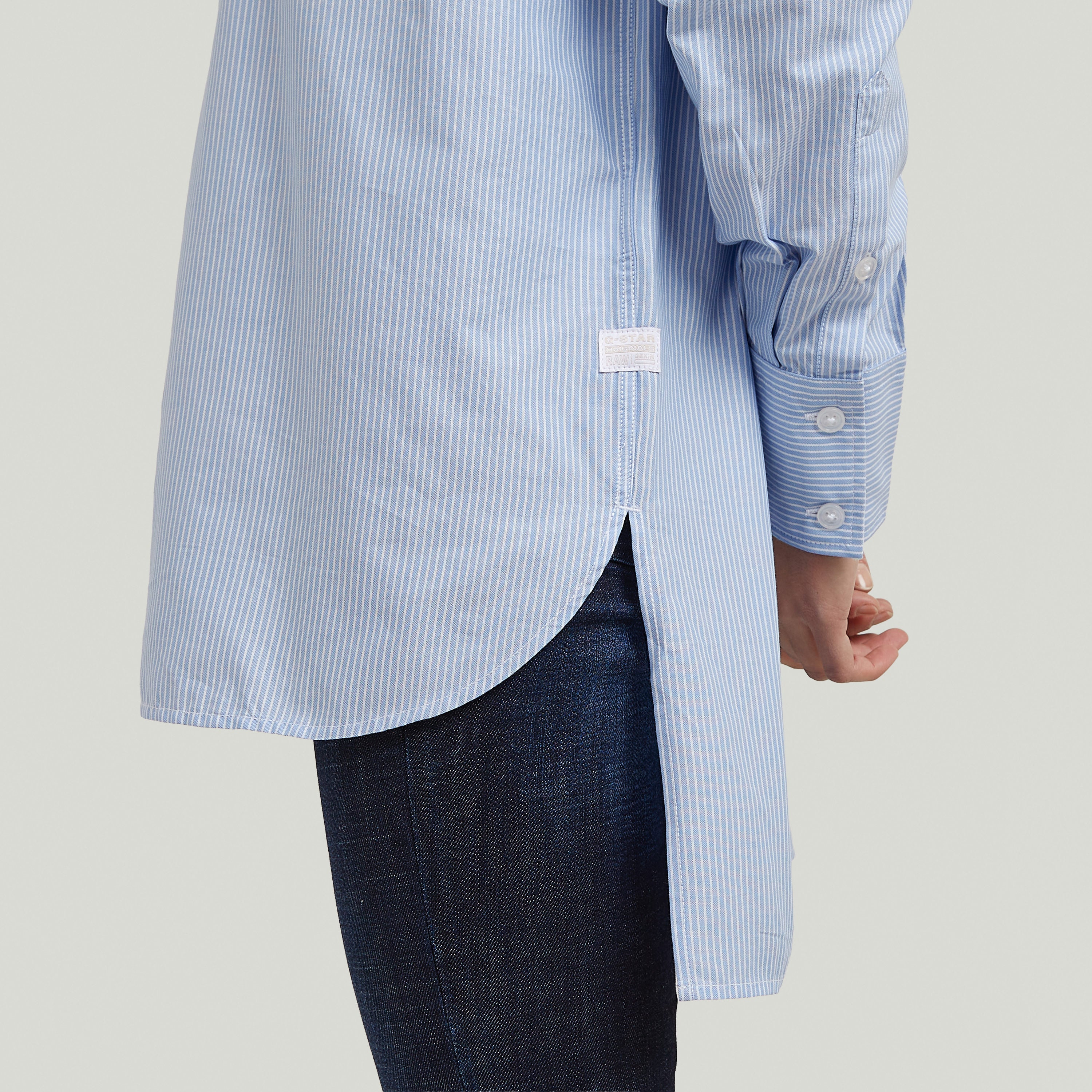 Imagen del lado de la camisa Relaxed Step Hem, destacando el bajo escalonado y el diseño de rayas verticales.
