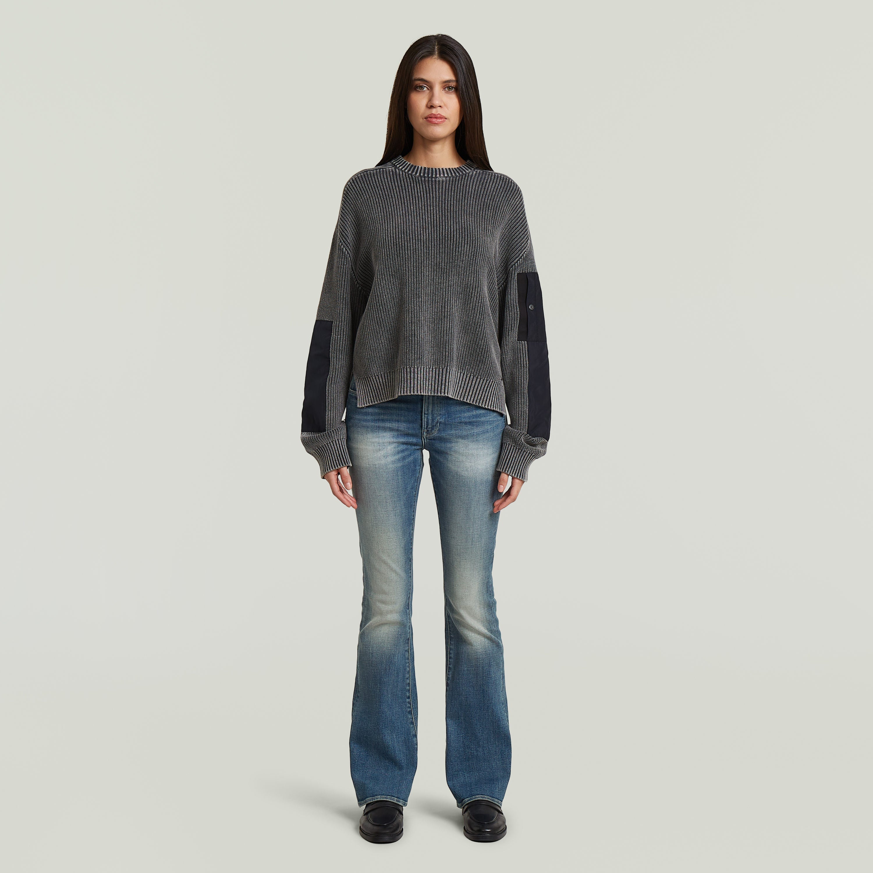 Woman wearing Washed Mixed Media Crew Pullover with flared jeans, standing against a neutral background.
