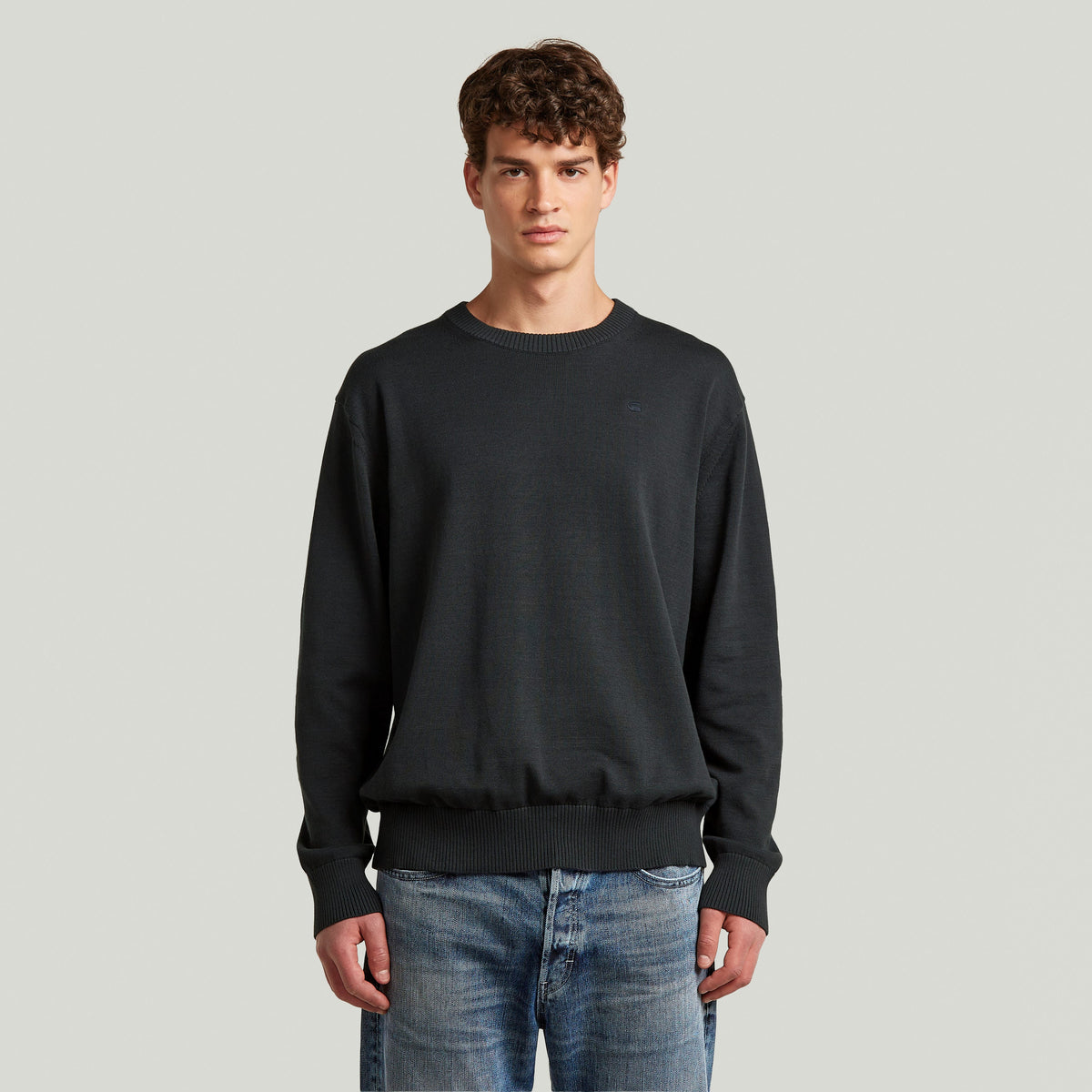 Classic knit pullover in dark color, featuring a round neck and long sleeves, perfect for casual wear.