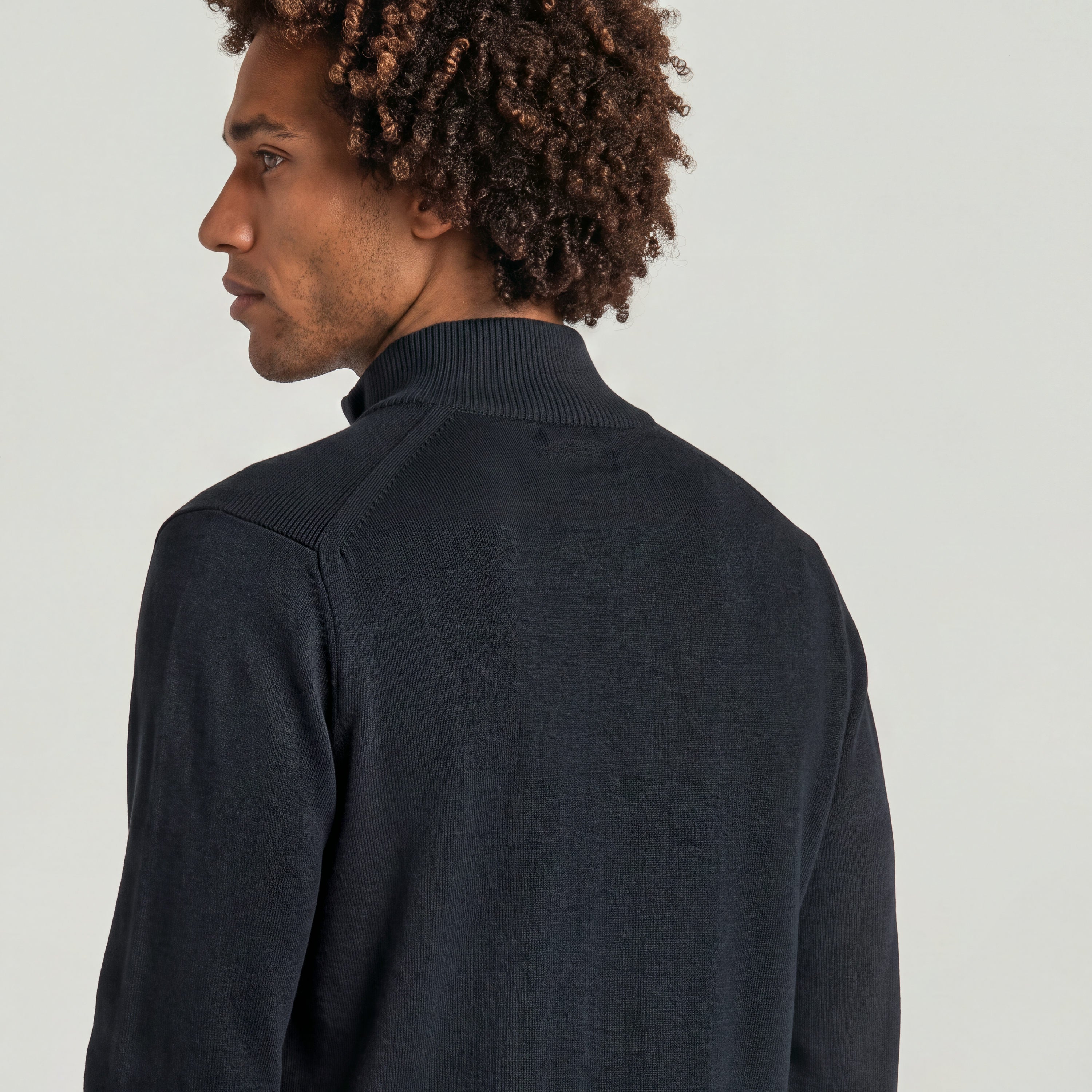 Hombre con suéter de punto half zip knit, vista trasera del cuello alzado y detalle de construcción de punto.