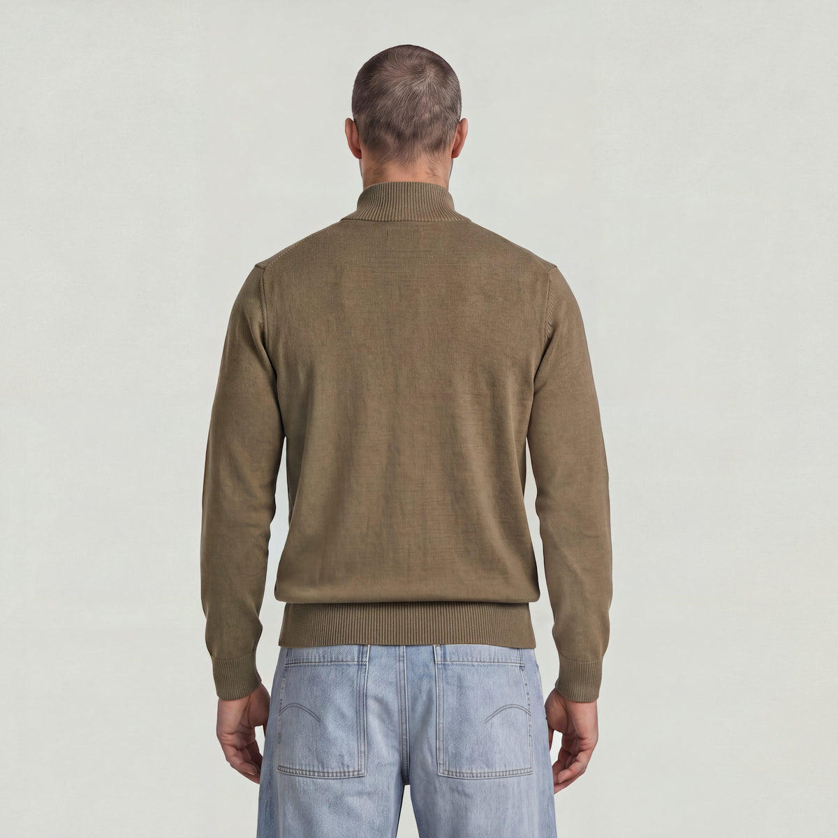 Back view of a man wearing the Core Refined Half Zip Knit sweater in olive green.