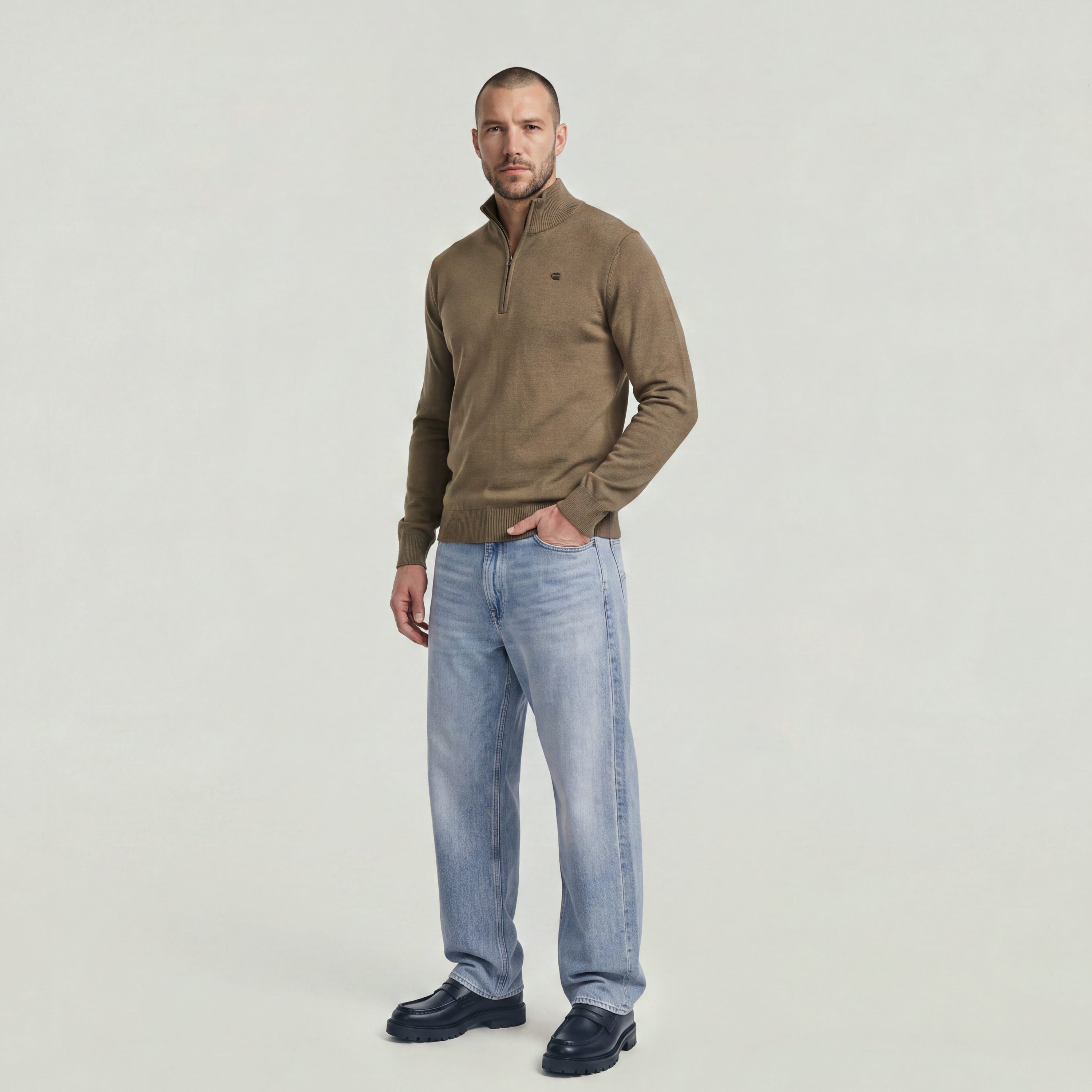 Man wearing a Core Refined half zip knit sweater with a modern design and jeans.