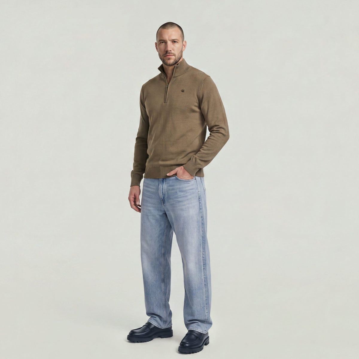 Man wearing a Core Refined half zip knit sweater with a modern design and jeans.