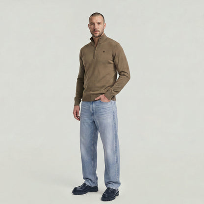Man wearing a Core Refined half zip knit sweater with a modern design and jeans.