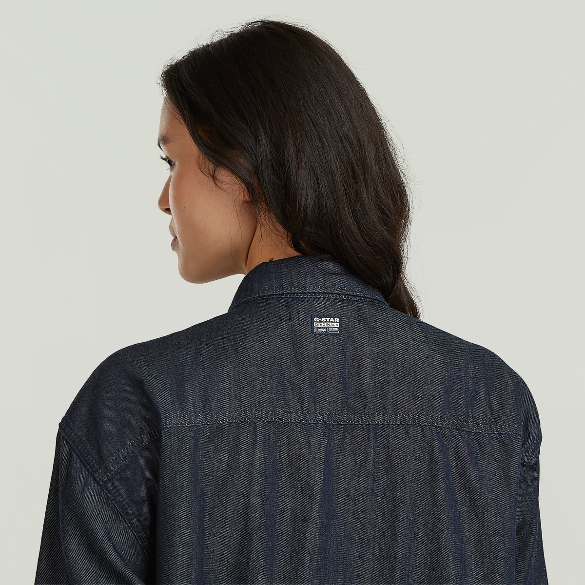 Mujer usando una camisa ligera Tucked-In Relaxed con diseño clásico y cómodo, vista desde atrás.