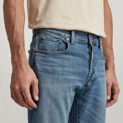 G-Star 3301 slim jeans on a model showcasing a medium indigo tone and classic five-pocket design.