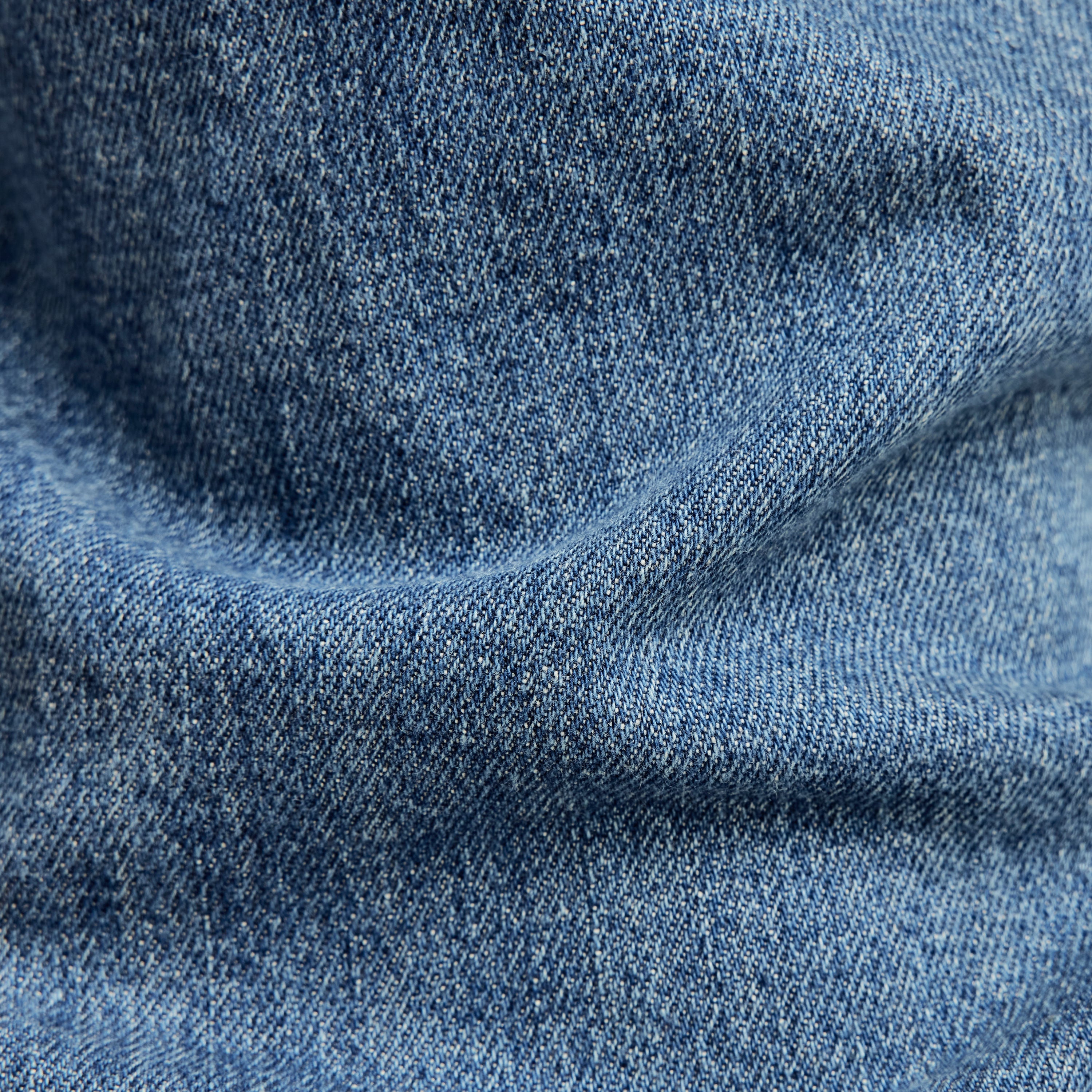 G-Star 3301 slim jeans denim fabric texture close-up, showcasing medium indigo color and detailed weave.