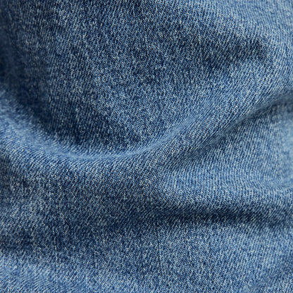 G-Star 3301 slim jeans denim fabric texture close-up, showcasing medium indigo color and detailed weave.