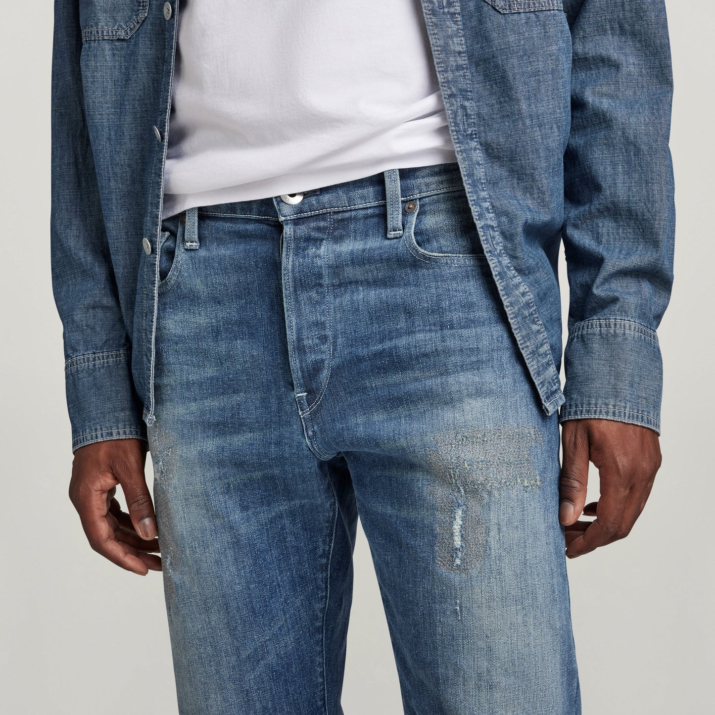 G-Star 3301 Slim jeans in blue denim with distressed detail and button fly, styled with a casual shirt.