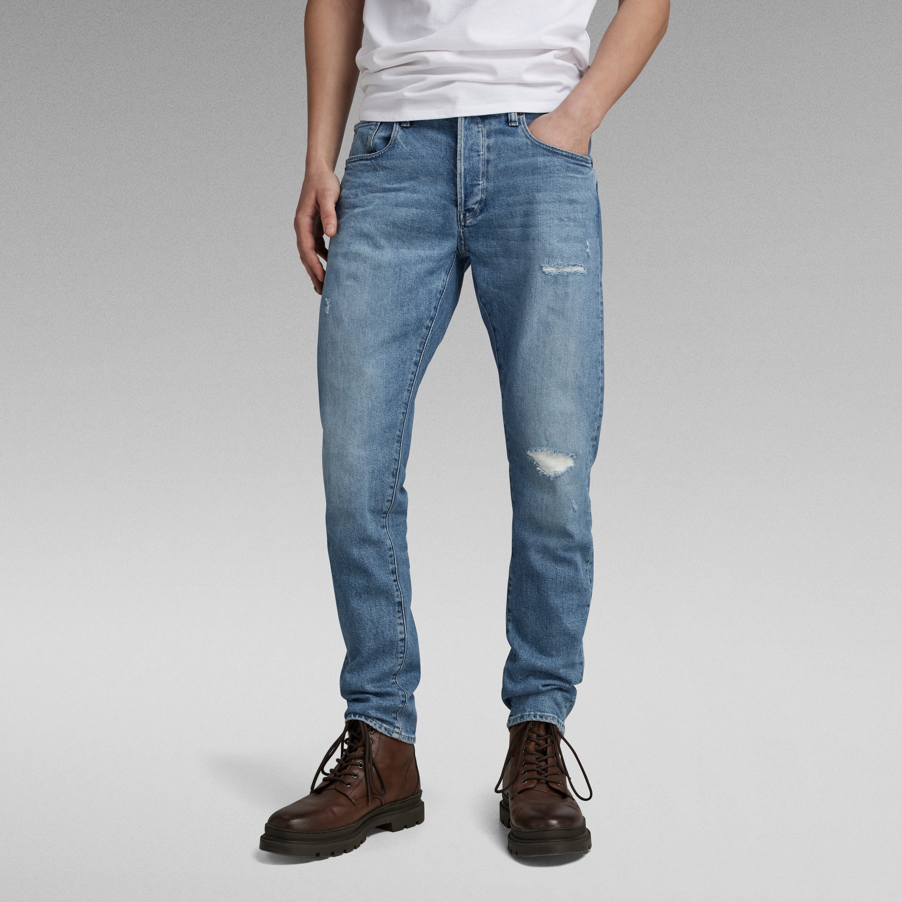 G-Star 3301 slim jeans model wearing light blue jeans with a white shirt and brown boots