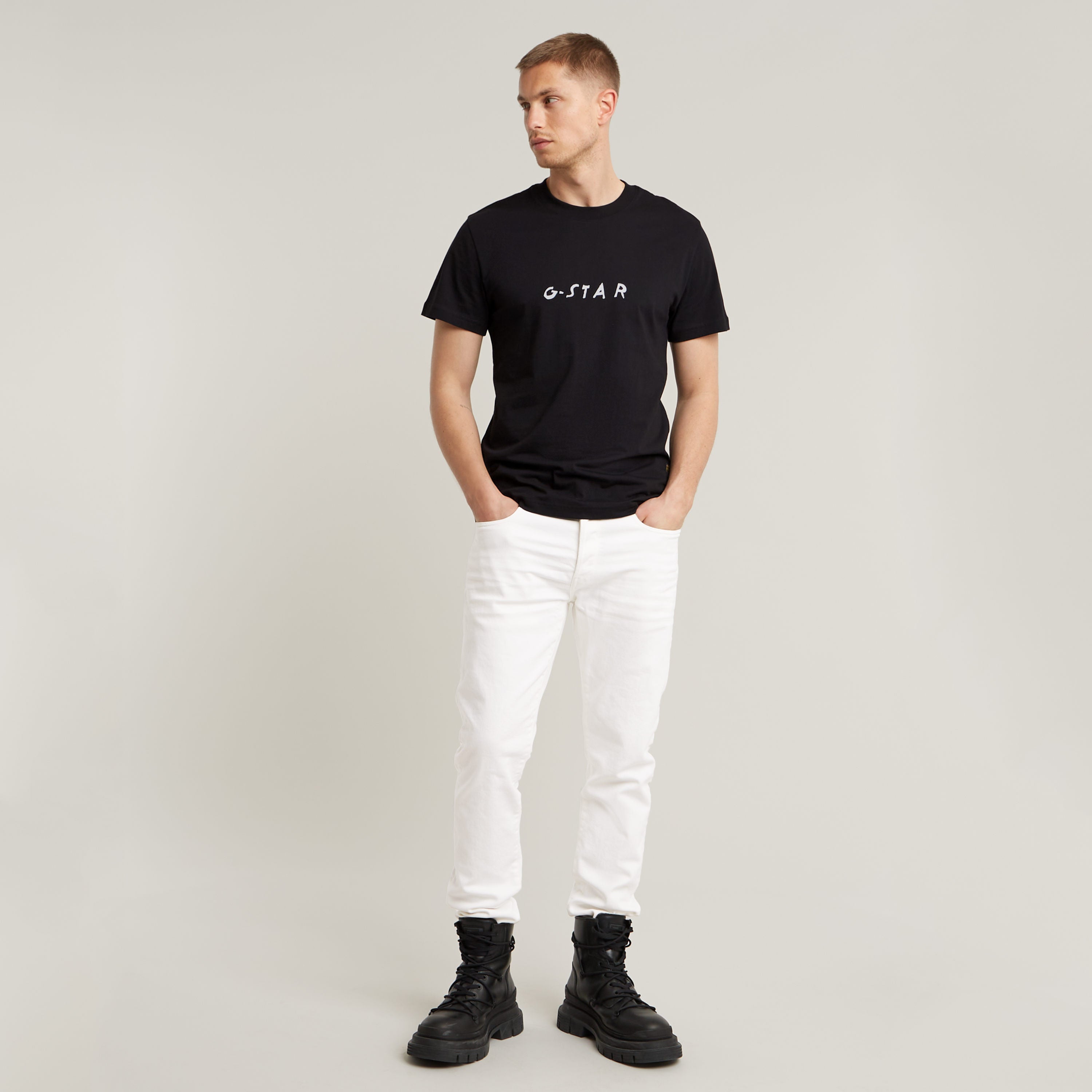 Modelo vistiendo jeans G-Star 3301 Slim con camiseta negra y botas, fondo neutro.