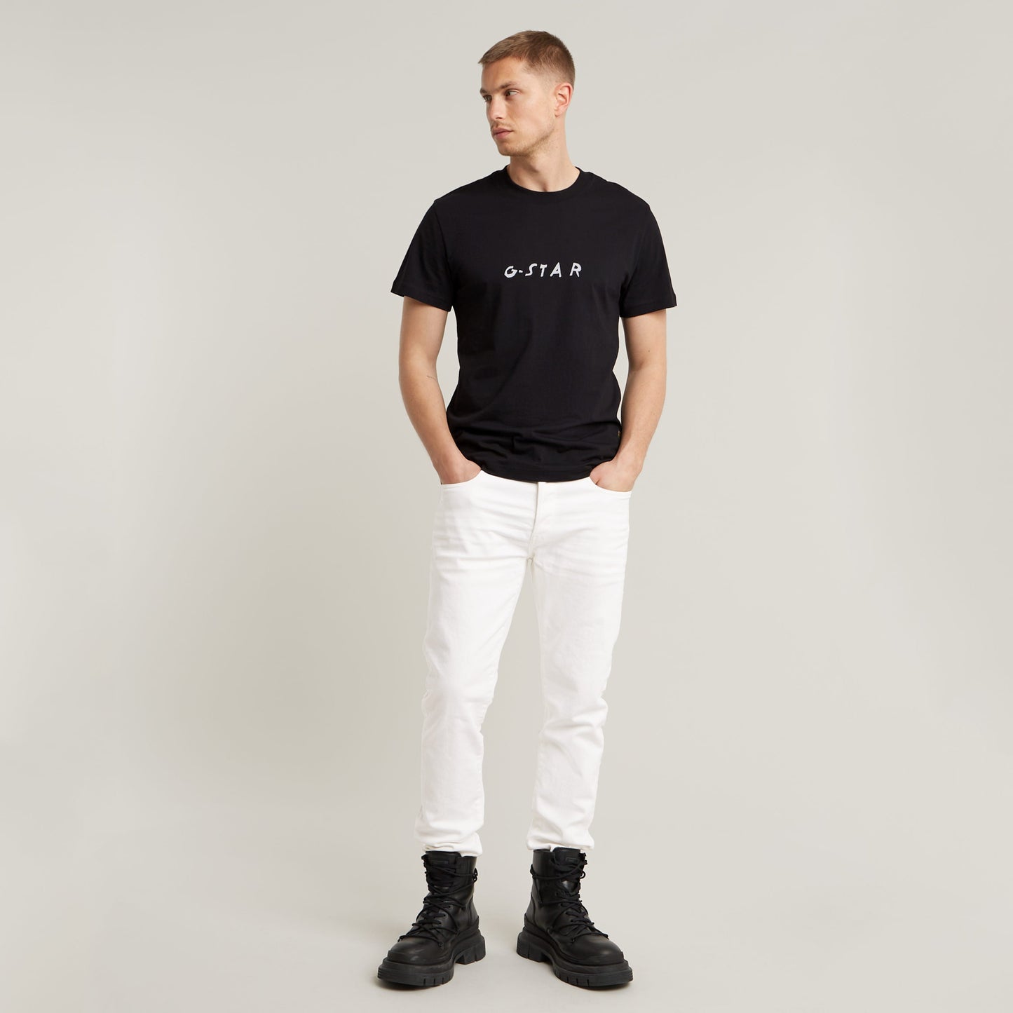 Modelo vistiendo jeans G-Star 3301 Slim con camiseta negra y botas, fondo neutro.