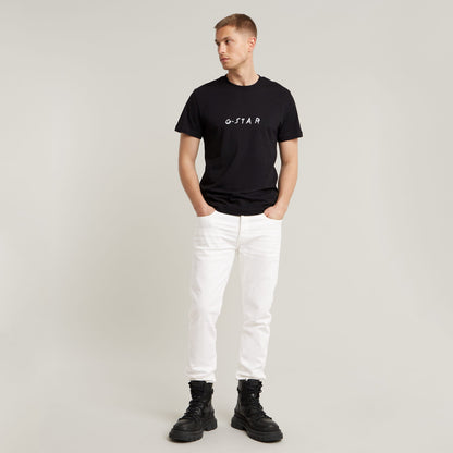 Modelo vistiendo jeans G-Star 3301 Slim con camiseta negra y botas, fondo neutro.