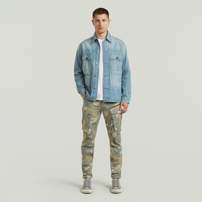 Modelo masculino vistiendo pantalones Rovic Zip 3D tapered pants y chaqueta de mezclilla en fondo neutro.