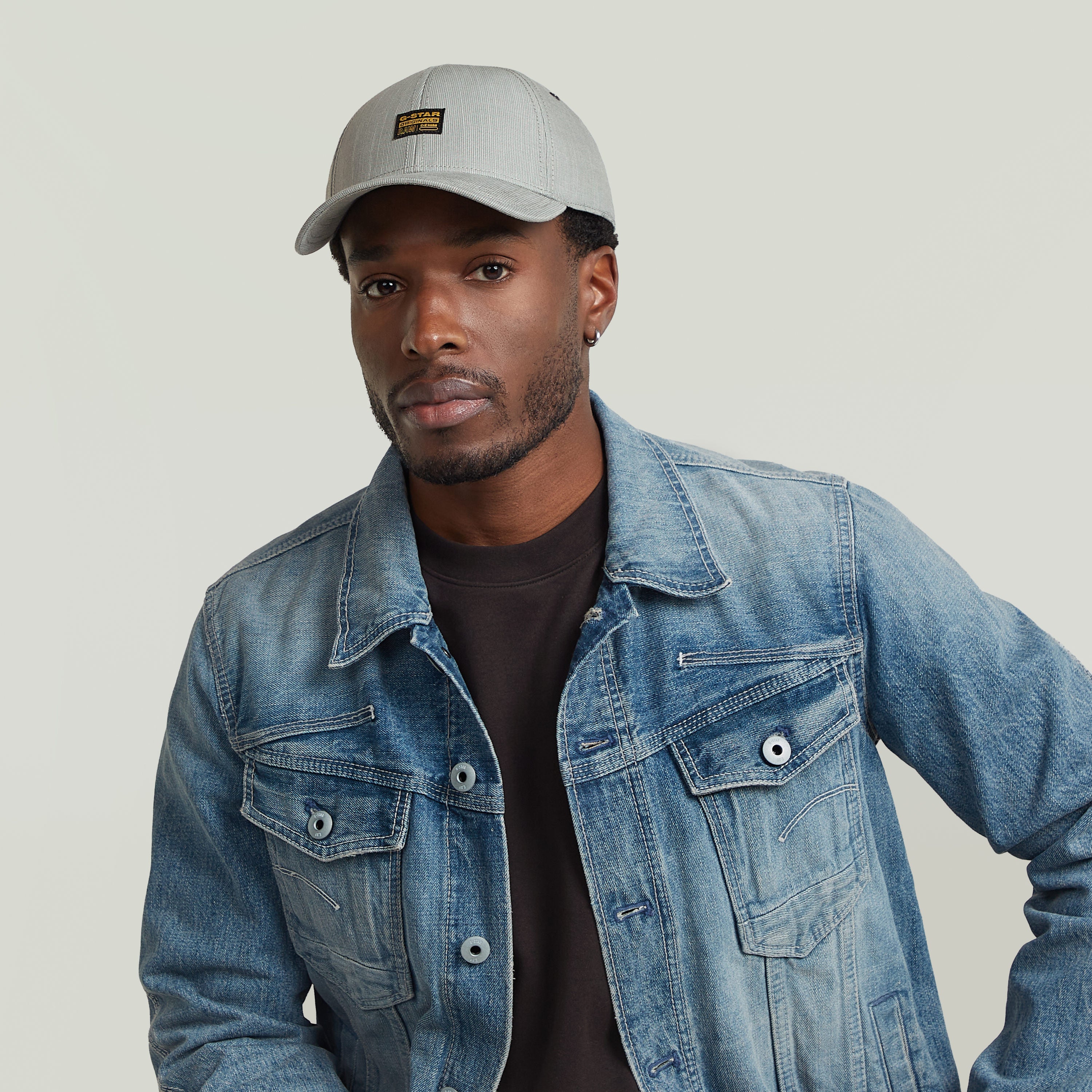 Hombre usando gorra G-STAR Originals con visera curvada y chaqueta de mezclilla.