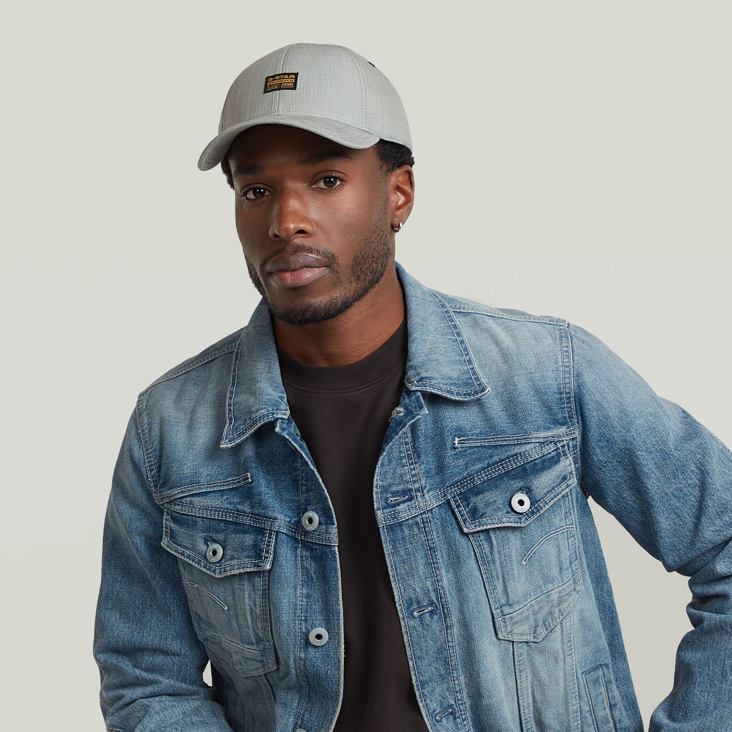 Hombre usando gorra G-STAR Originals con visera curvada y chaqueta de mezclilla.