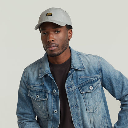 Hombre usando gorra G-STAR Originals con visera curvada y chaqueta de mezclilla.