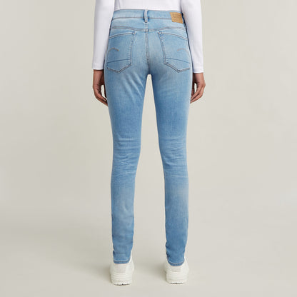 Mujer usando jeans 3301 skinny de corte pitillo en azul claro desde atrás, con detalles clásicos y etiqueta en la parte trasera.