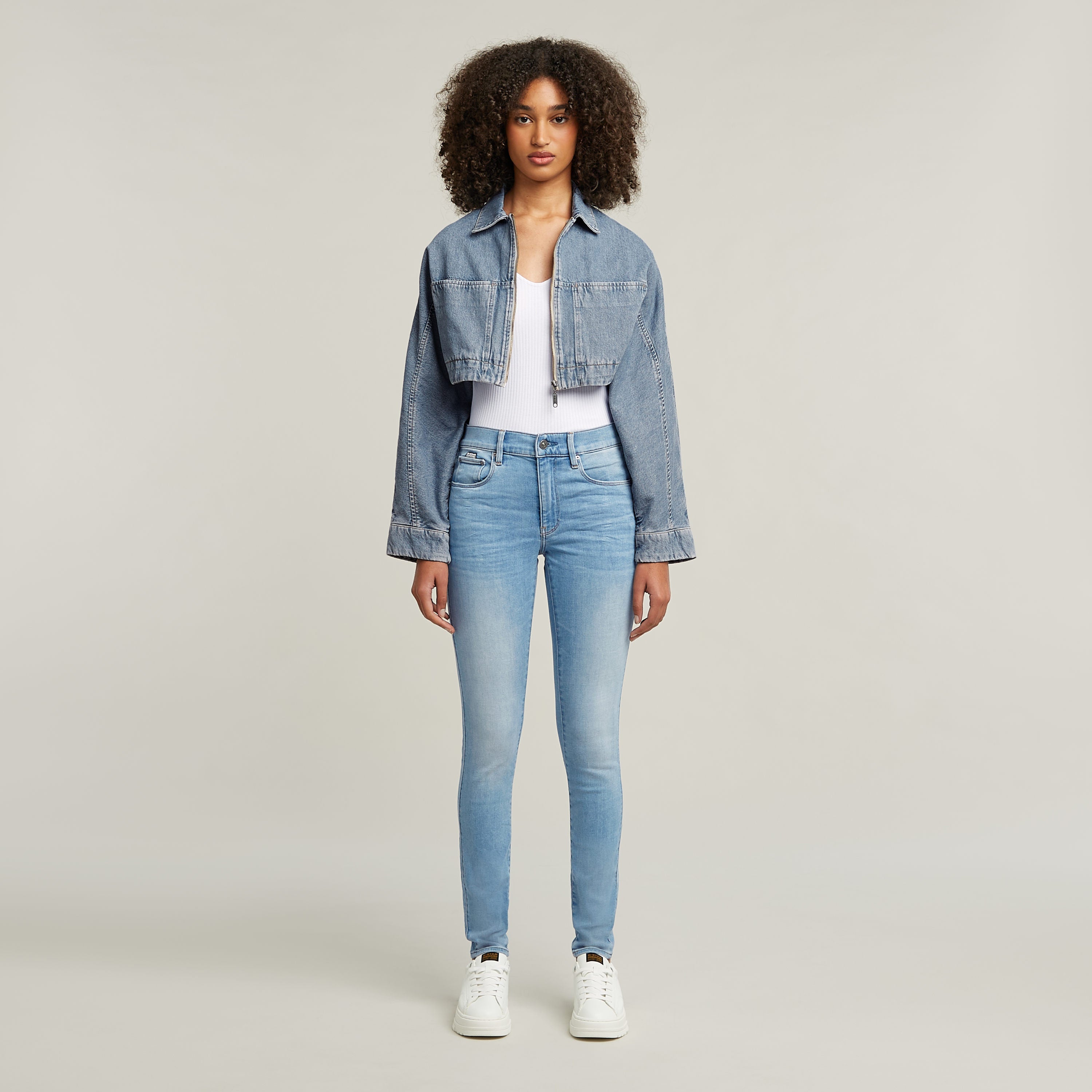 Mujer luciendo jeans 3301 skinny, de corte pitillo en tono azul claro, combinados con chaqueta de mezclilla.